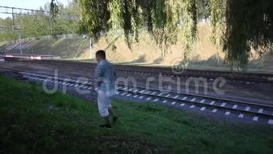 一个年轻人沿着铁轨走。 一辆通勤列车<strong>驶过</strong>